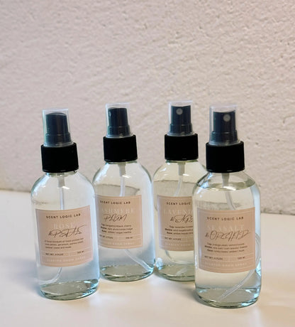 Four spray bottles with labels on a light surface and textured wall background