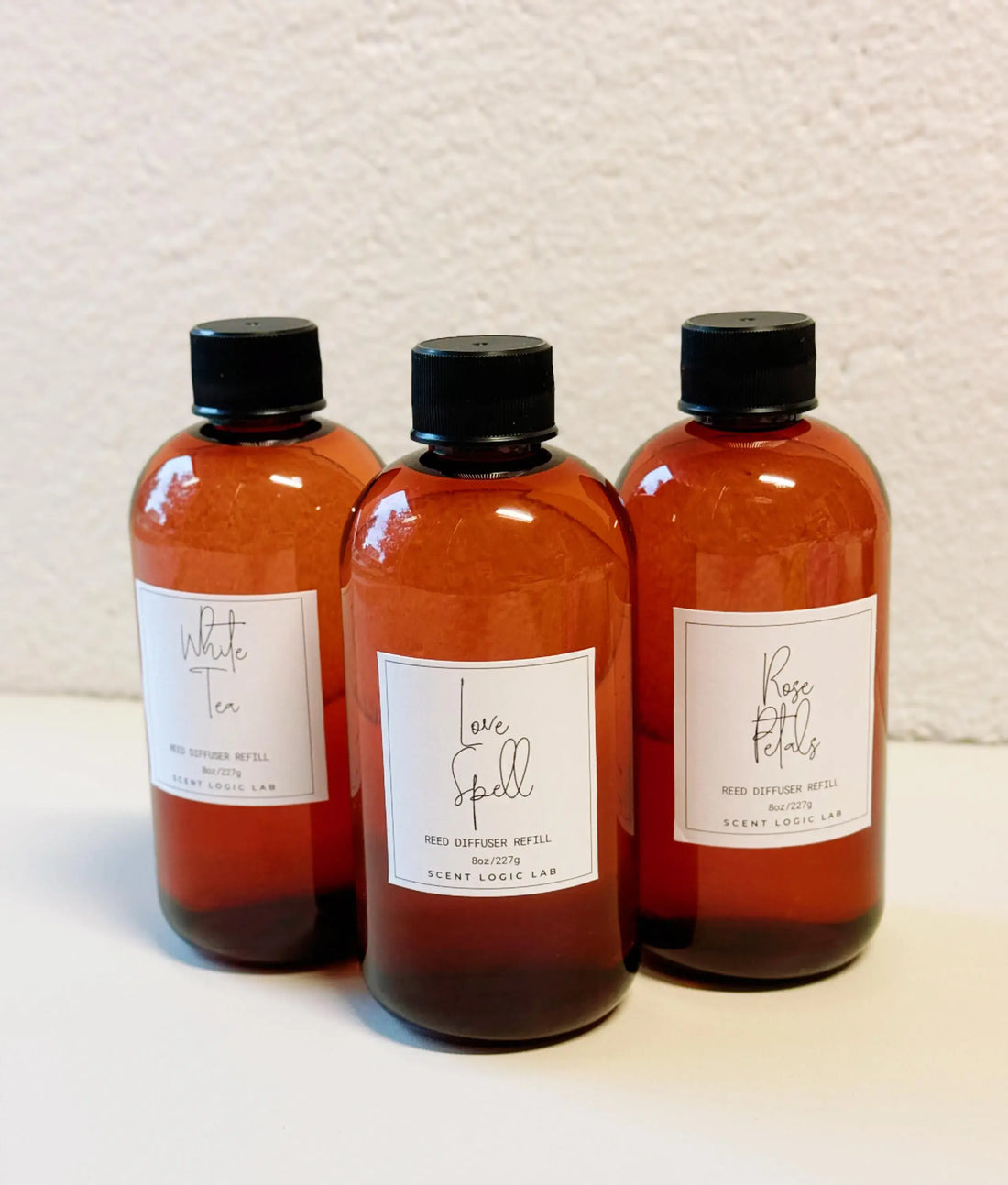 Three amber-colored bottles with black caps on a textured beige background