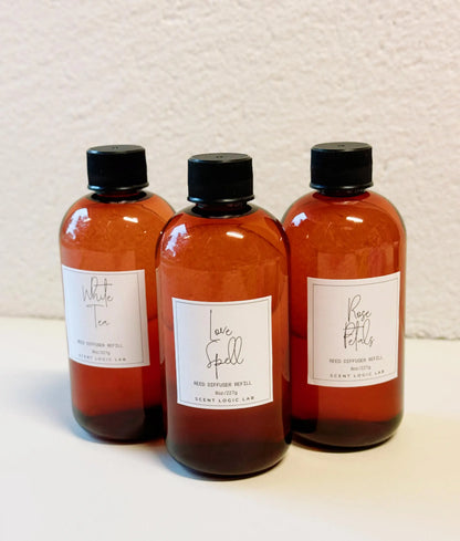 Three amber-colored bottles with black caps on a textured beige background